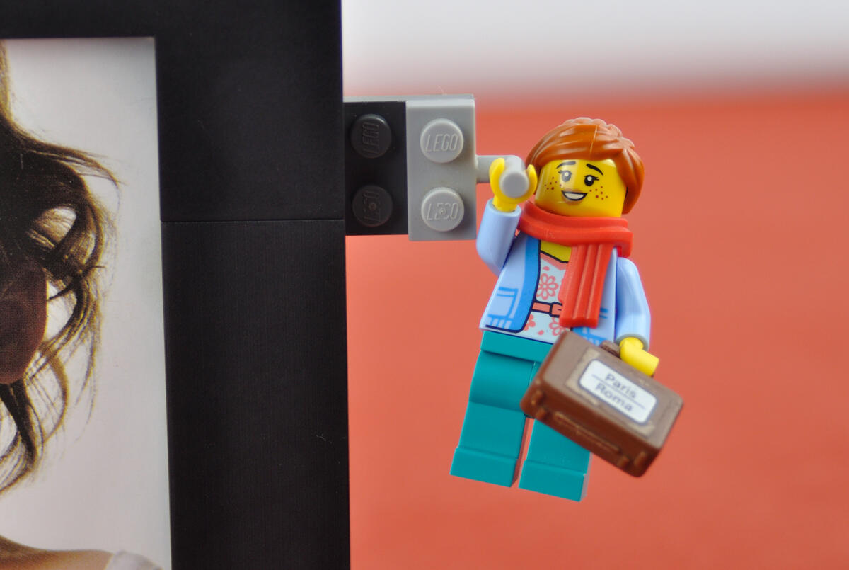 A LEGO woman holding a travel suitcase hanging off an anyframe photo frame